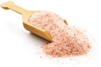 Himalayan salt in a wooden scoop. Isolated on a white background.